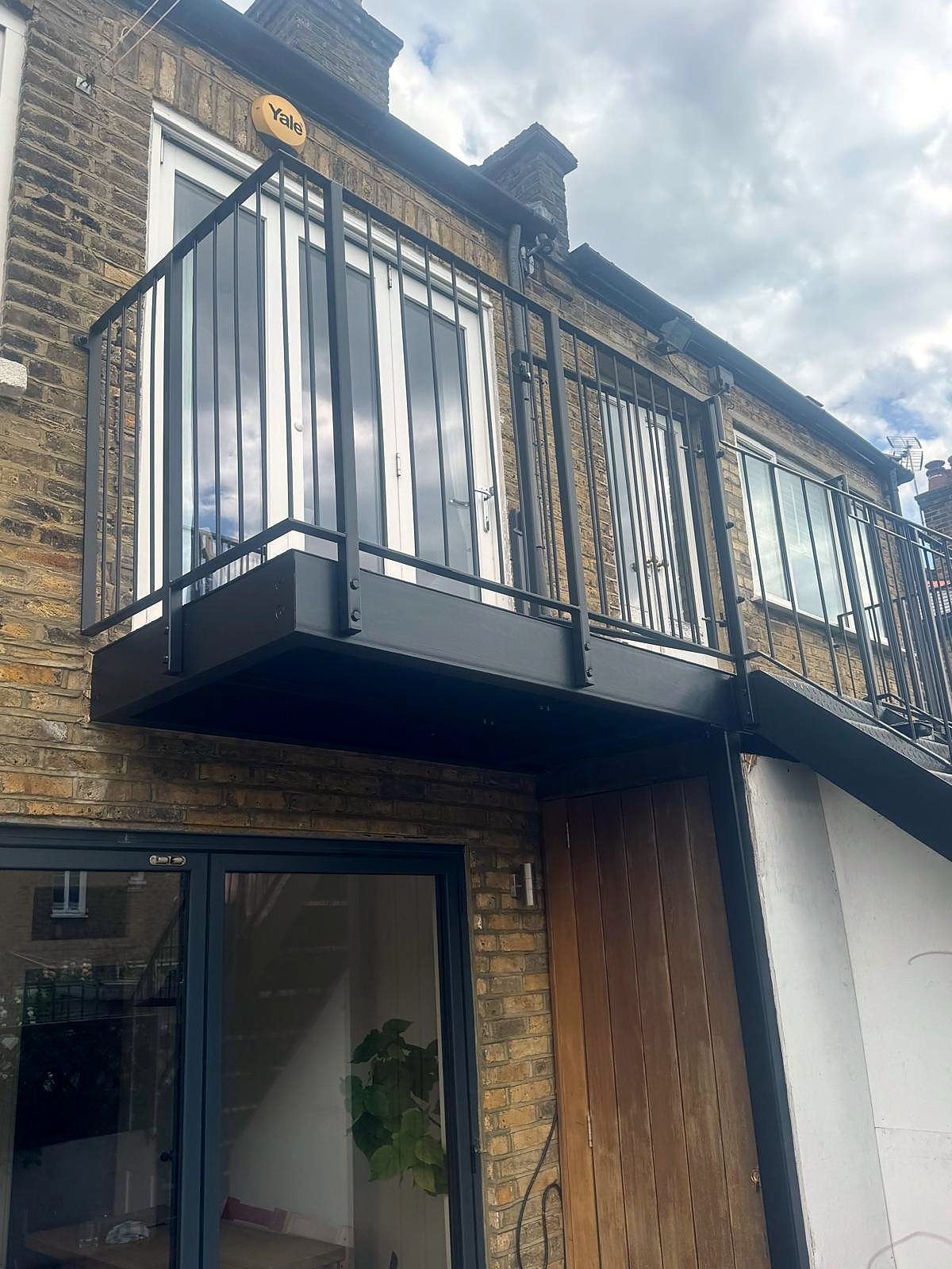 Black steel balcony with bar railings on the back of a London stock-brick house